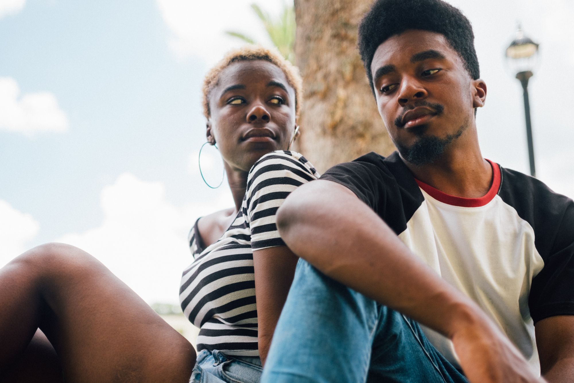 A seated Black man and Black woman look askance, skeptically