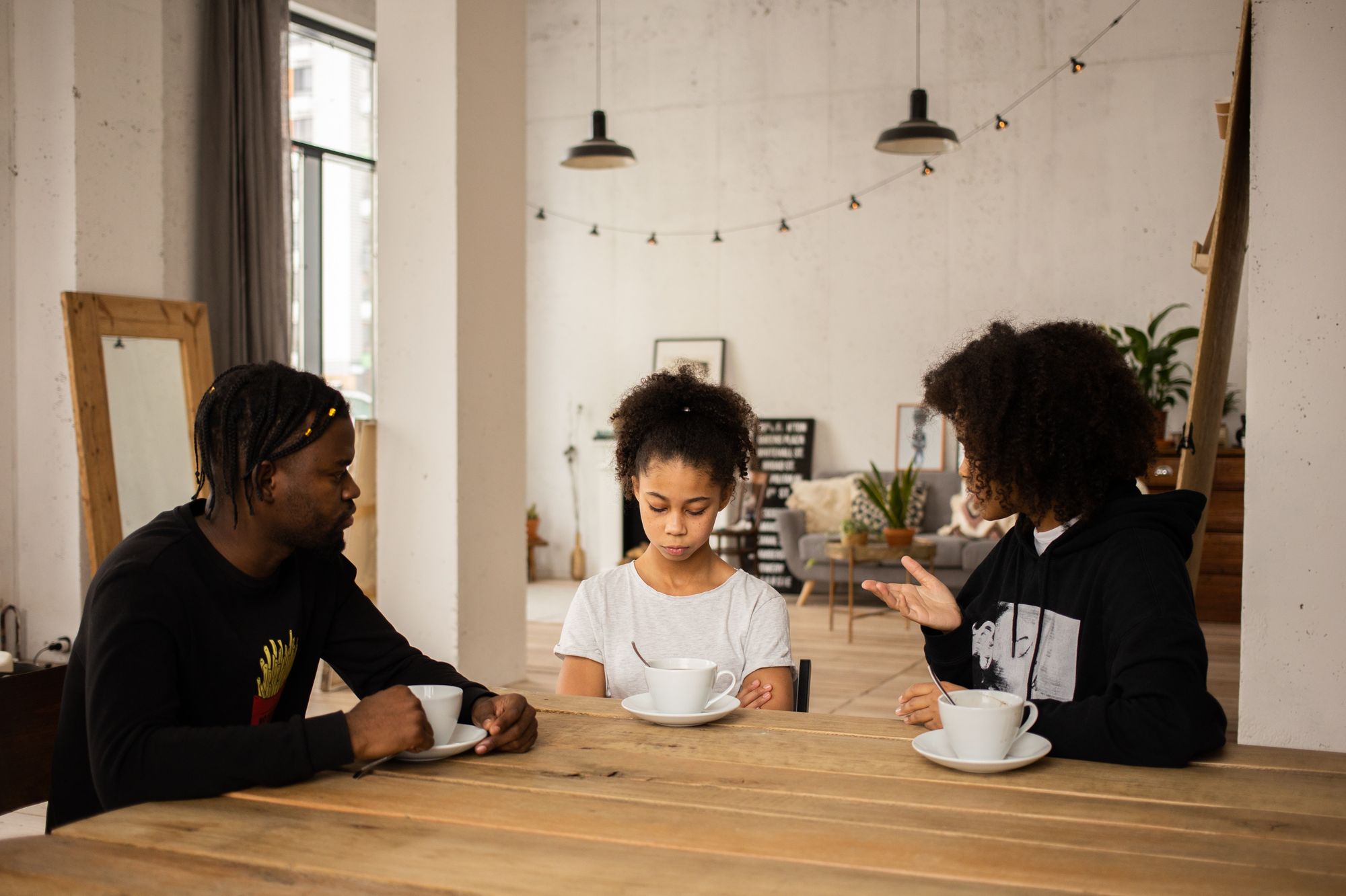 A Black man and Black woman instruct their Black daughter.